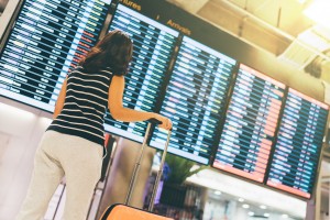 Asian woman traveler looking at flight information screen in airport