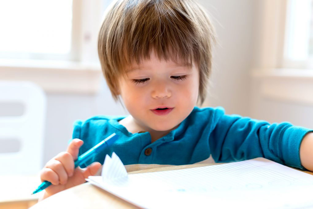 Toddler boy, at a table holding a pen