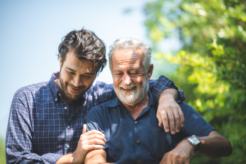 Two men holding each other in an outside setting