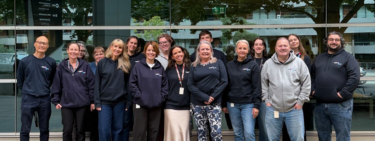 Group of colleagues wearing navy hoodies smiling at camera