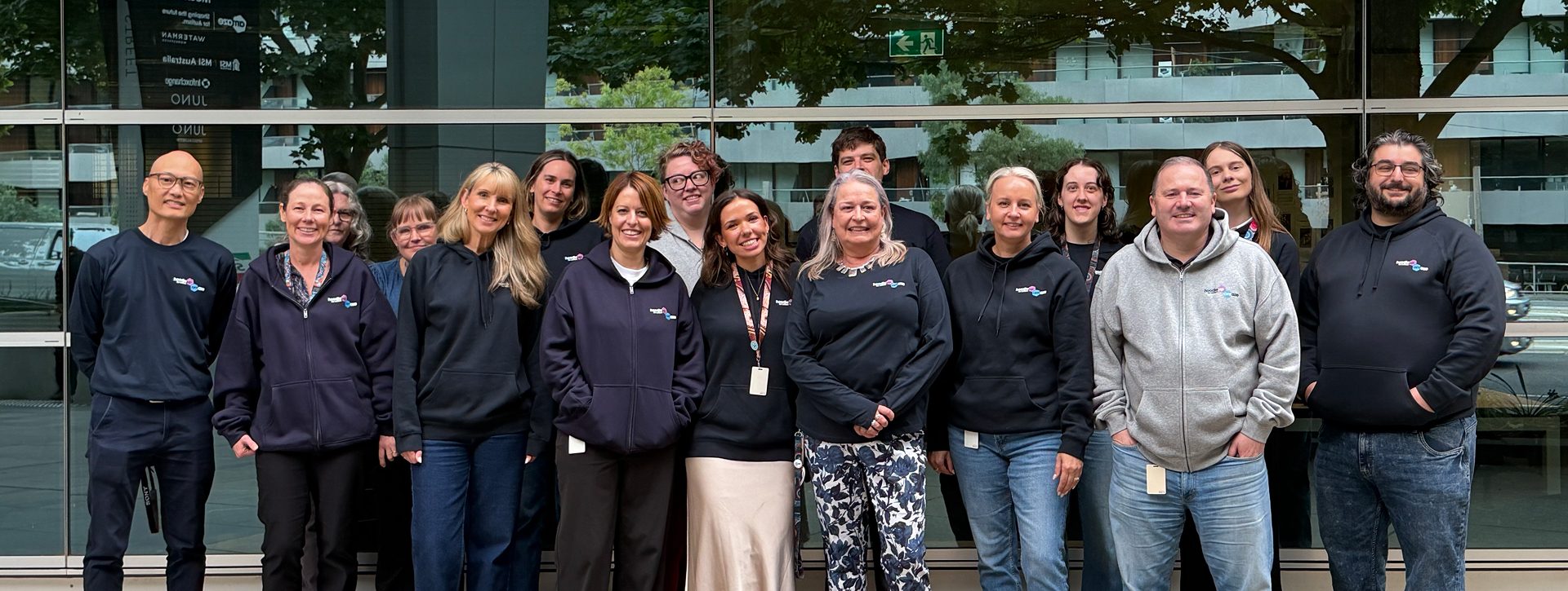 Group of colleagues wearing navy hoodies smiling at camera